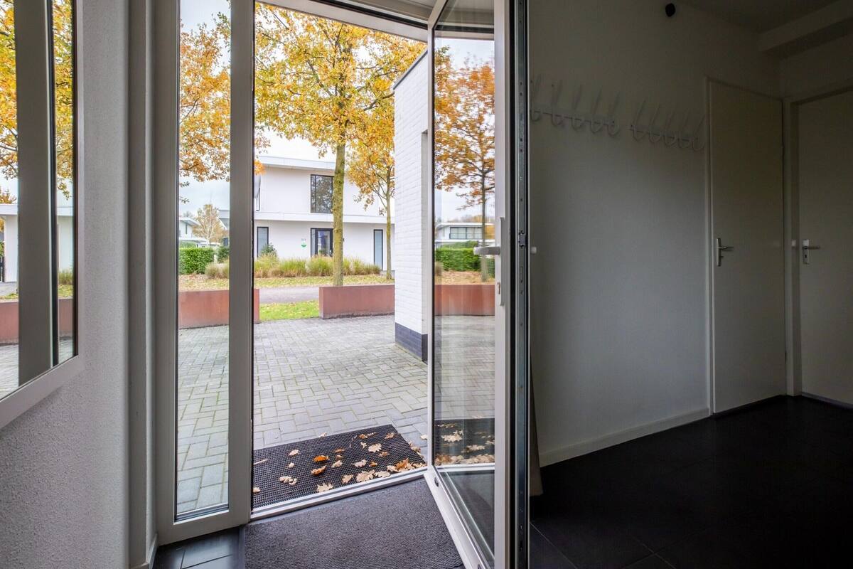 A modern interior with a glass door leading to an outdoor area with autumn foliage.