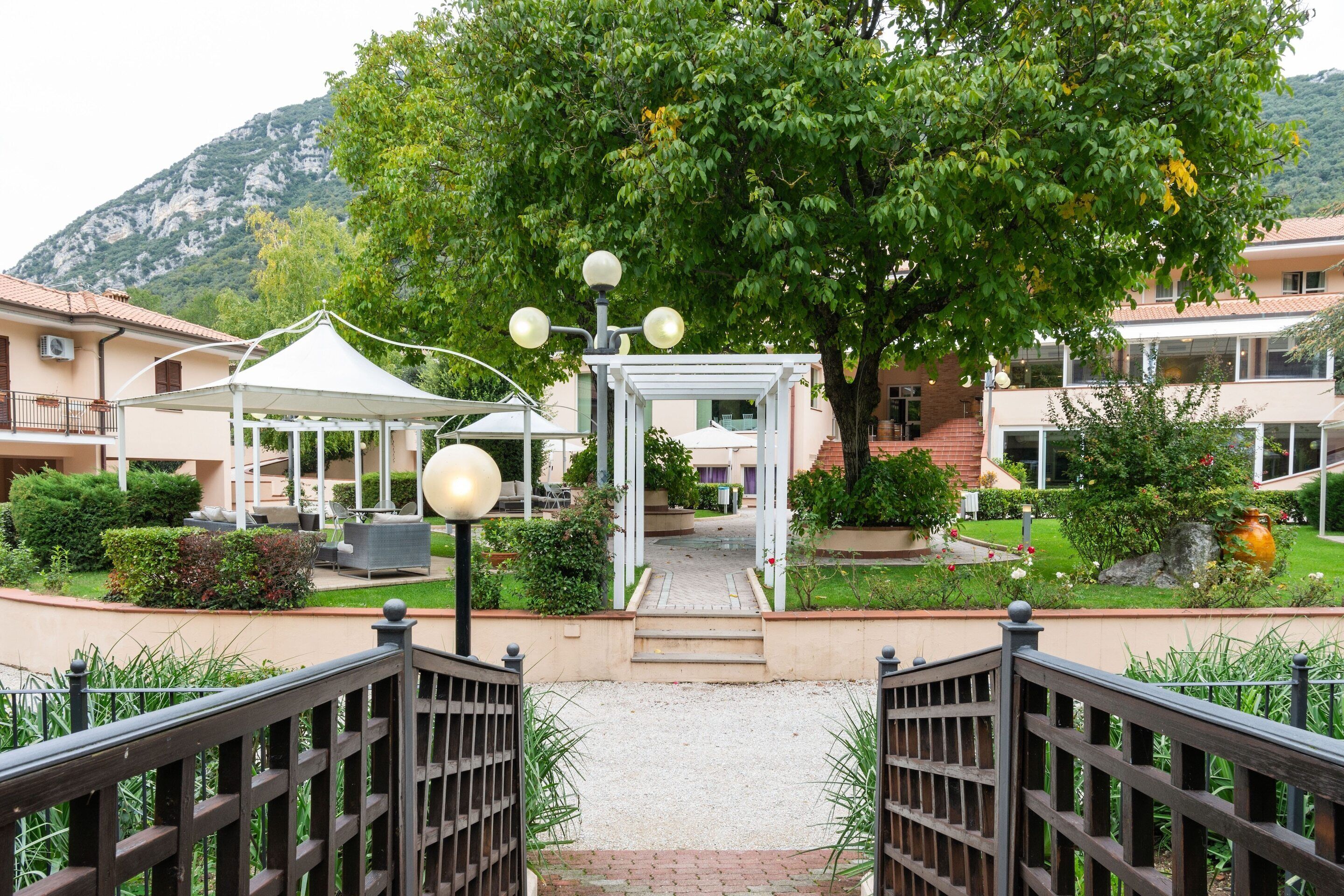 A hotel entrance with a covered walkway, a gazebo, and a mountain backdrop.