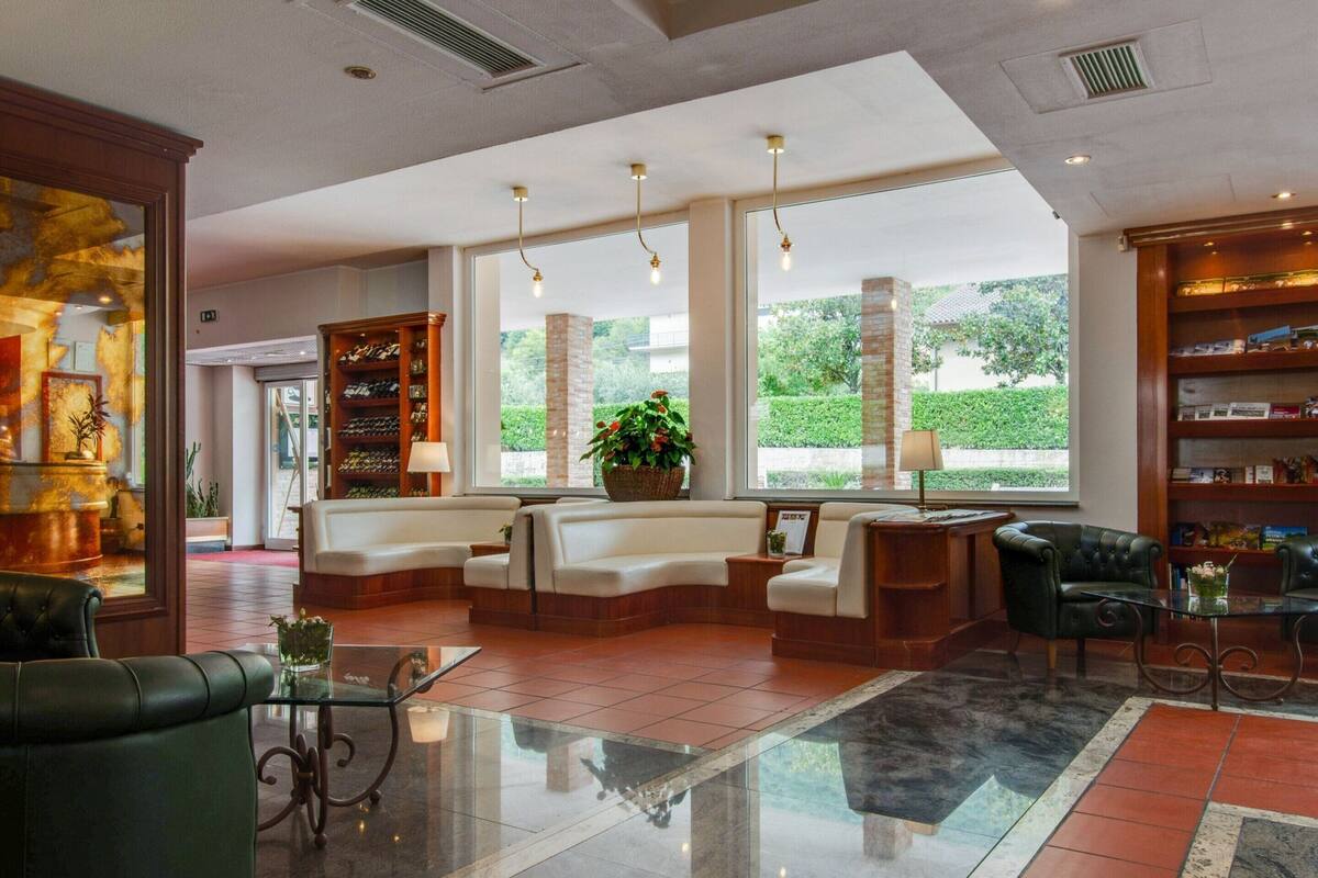 A spacious lobby with a reception desk, seating area, and a large window offering a view of greenery outside.