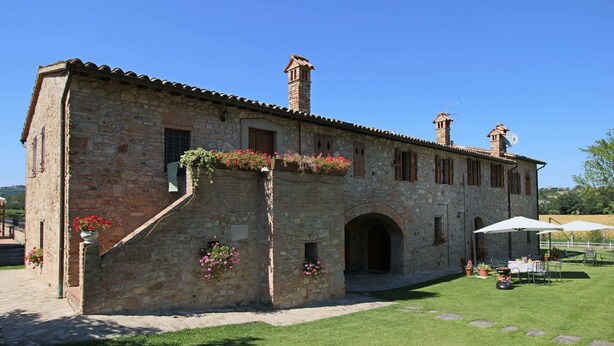A stone building with a courtyard, featuring a covered outdoor seating area with umbrellas.