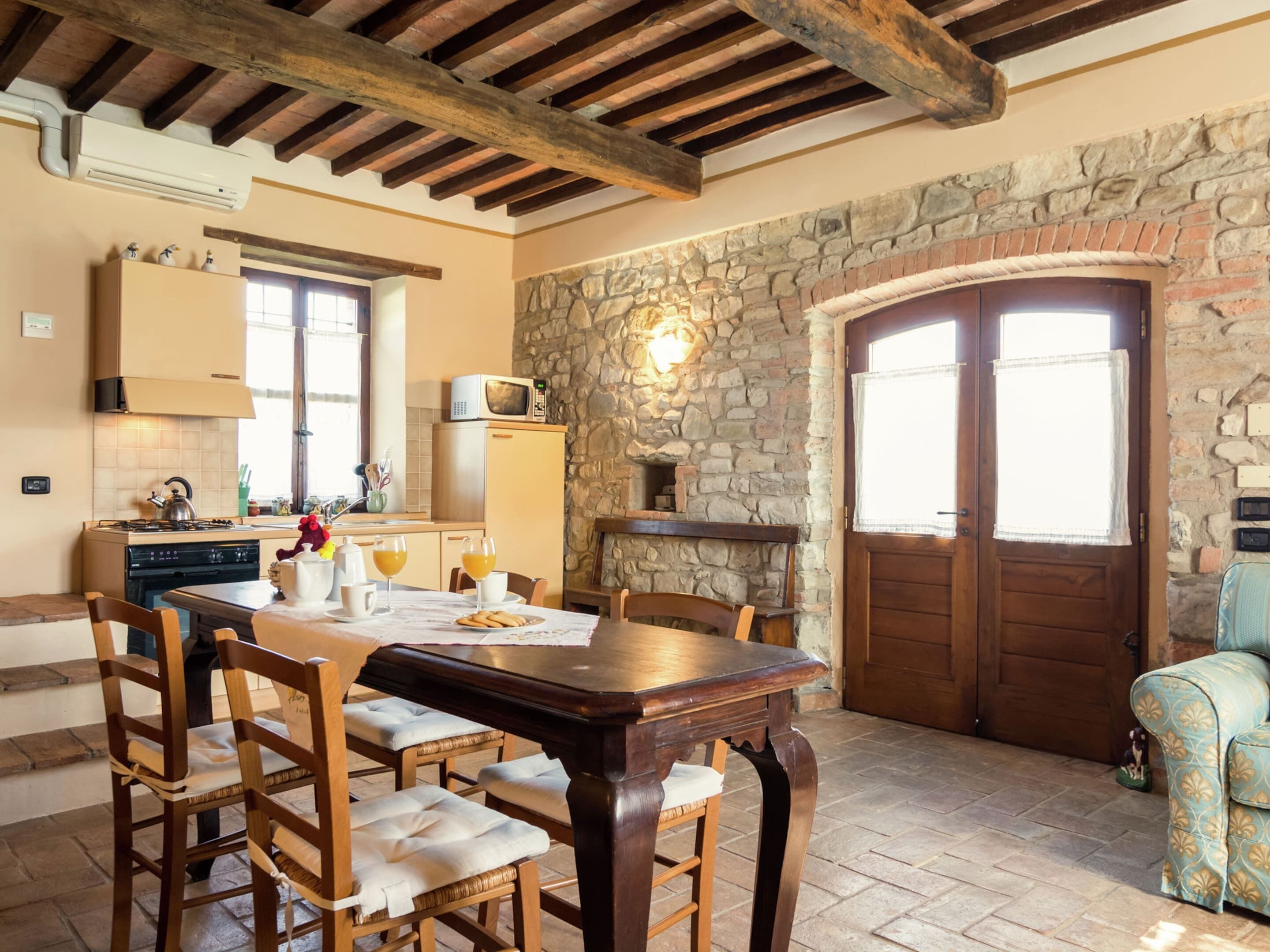 A dining area with a wooden table and chairs, a stone wall, and a wooden door.