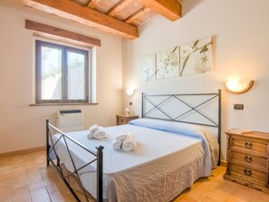 Une chambre à coucher comprenant un lit, une fenêtre, un radiateur, une lampe fixée au mur et une commode en bois.