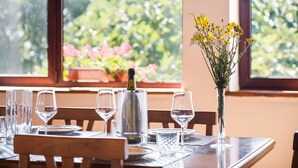 Une table à manger dressée avec des verres à vin, une bouteille et un vase rempli de fleurs.
