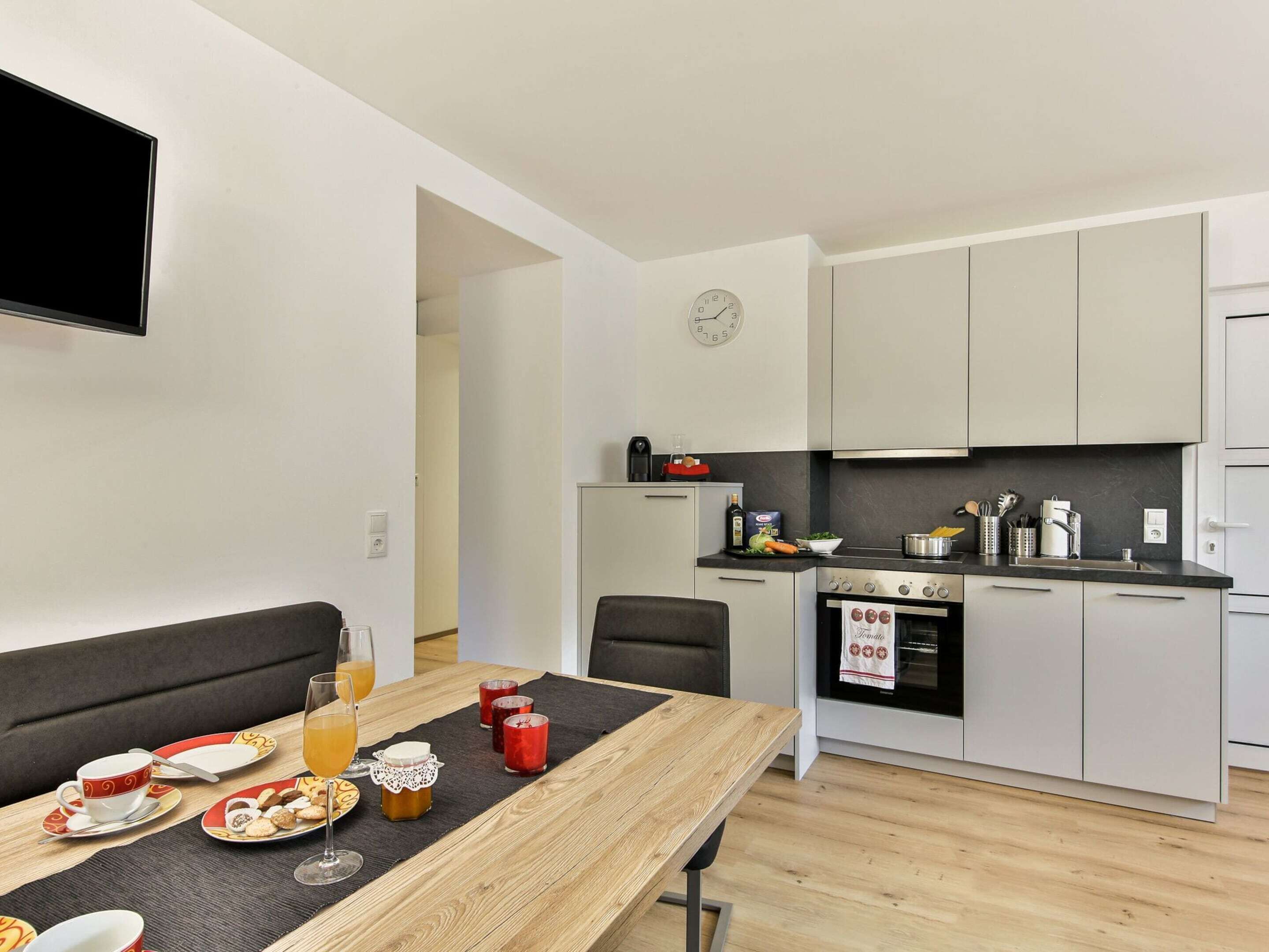 Een moderne keuken met een eethoek, een flatscreen televisie en een klok aan de muur.