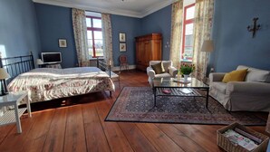 Ein Zimmer mit einem Bett, zwei Sesseln, einem Sofa, einem Glastisch und einem Holzschrank.