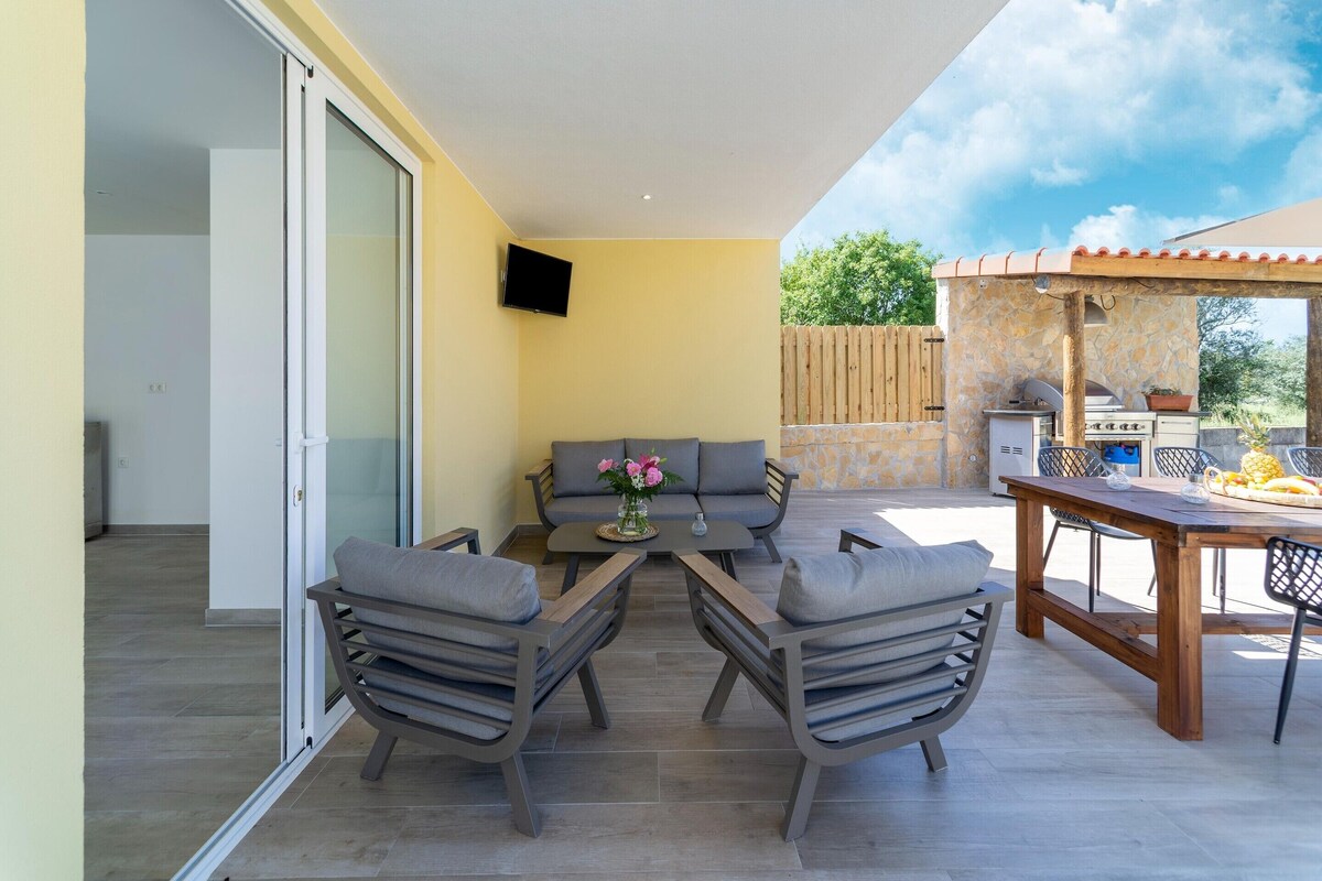 An outdoor patio with a sofa, chairs, a table, and a grill area.