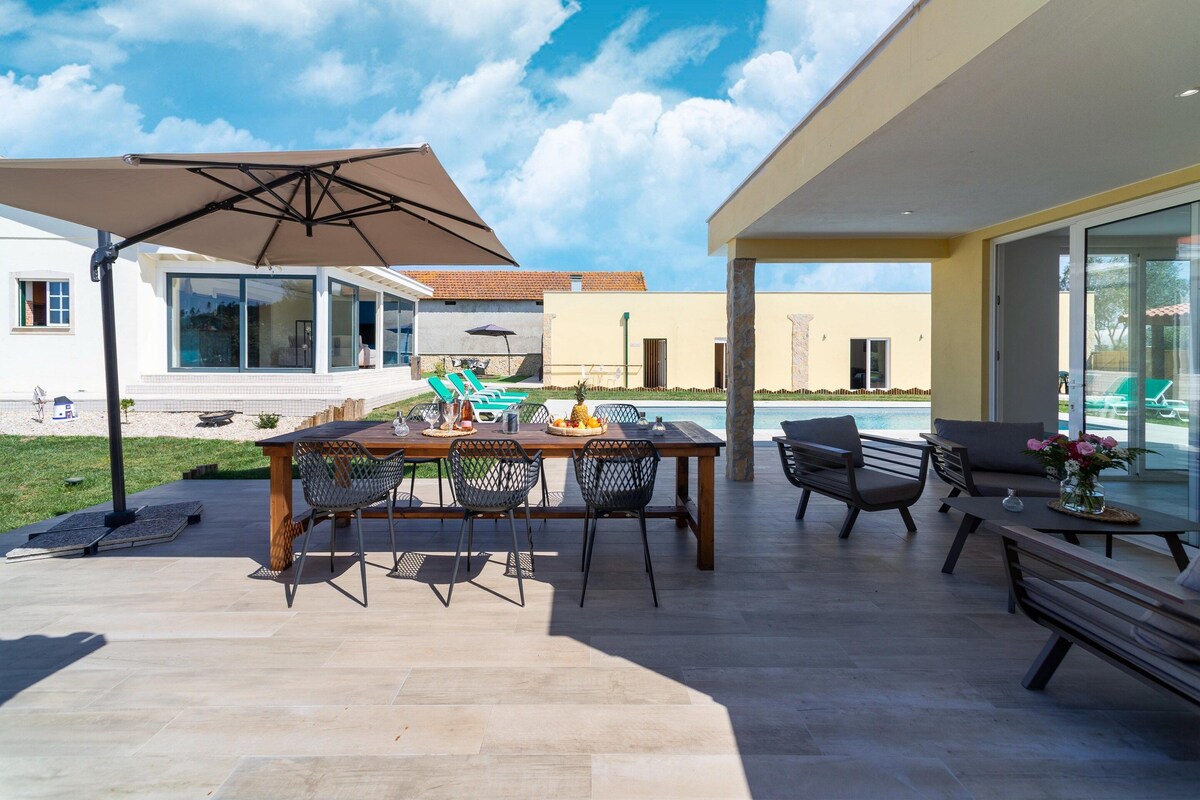 An outdoor patio with a dining table, chairs, and a pool area.