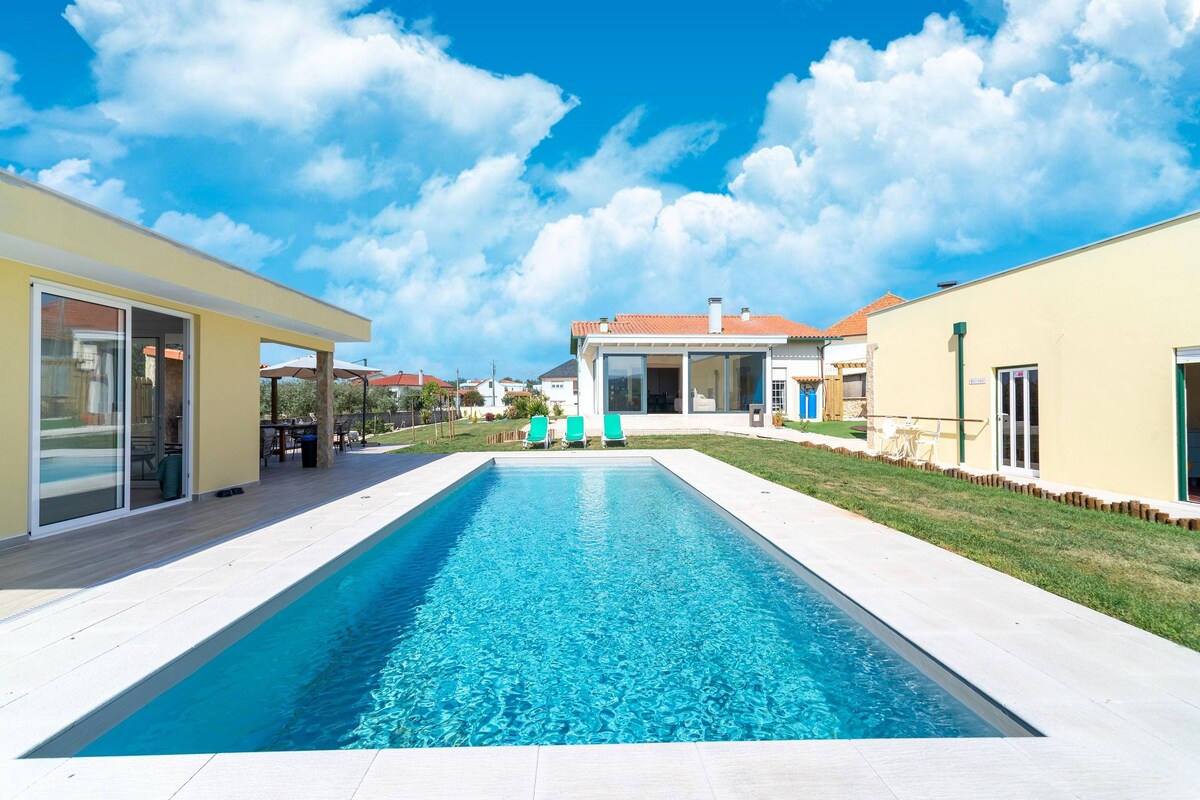 A swimming pool with a clear blue water surface, surrounded by a paved deck.