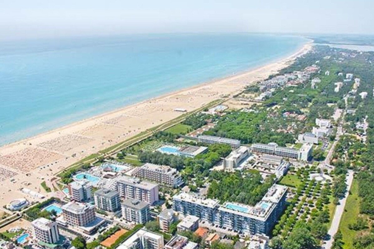 Luftaufnahme eines Küstenresorts mit mehreren Hochhäusern, einem Sandstrand und freiem Blick auf den Ozean.