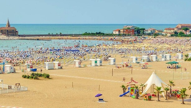 Ein überfüllter Strand mit vielen Sonnenschirmen und Strandkörben.