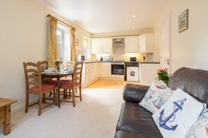 A compact living space with a dining area, kitchenette, and a leather sofa with nautical-themed pillows. - Host Stay No 12 in Alnwick (Alnwick)