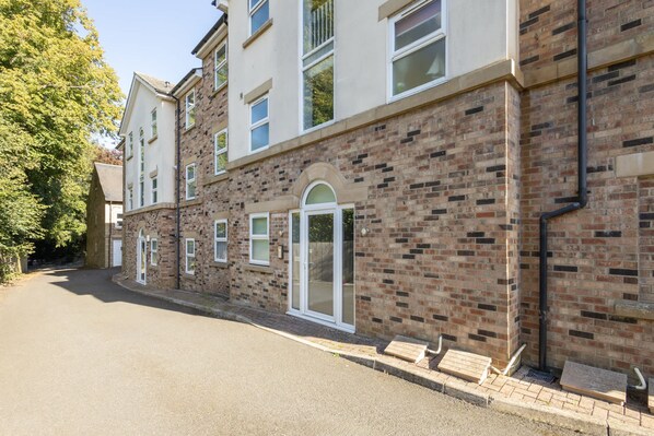 A multi-story residential building with a brick facade, white-framed windows, and a central entrance with a glass door. - Host Stay No 12 in Alnwick (Alnwick)