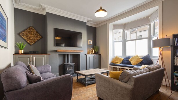 Una sala de estar con chimenea, sofás, televisor y estantería.