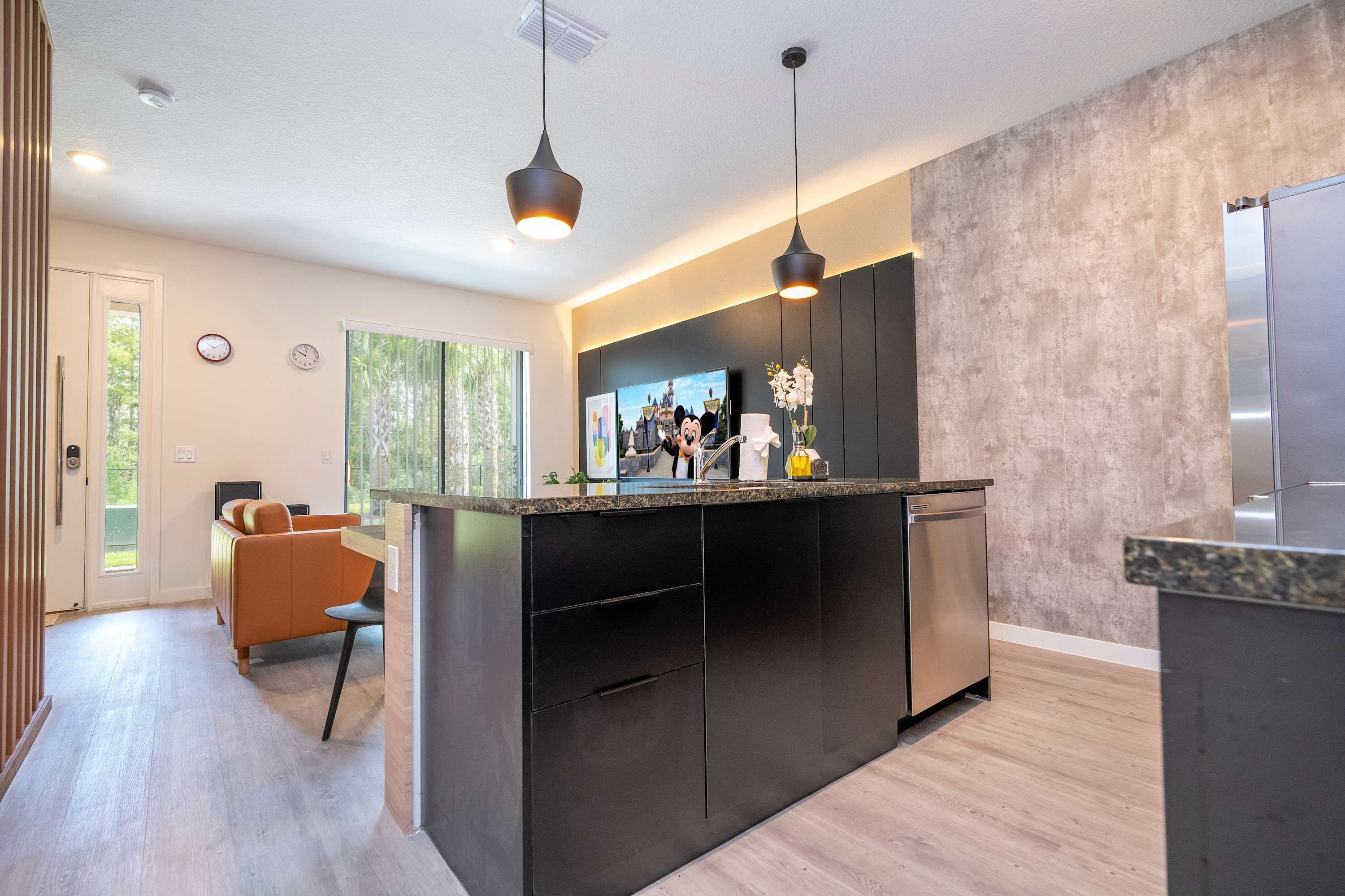 A modern kitchen with a central island, black cabinets, and stainless steel appliances.