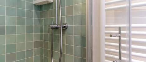 A shower area with a glass door and a metal showerhead.