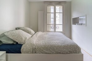 A bedroom with a bed, a window, and a radiator.
