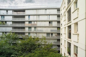 A multi-story residential building with balconies, a flat facade, and a surrounding area with trees. - Modern & Contemporary 1BD Flat, Île Saint-Louis (Paris)