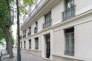 A multi-story building with a white facade, large windows, and balconies with metal railings. - Modern & Contemporary 1BD Flat, Île Saint-Louis (Paris)