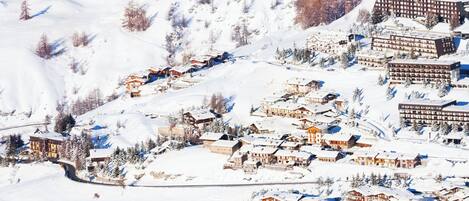 A snow-covered mountain village with traditional wooden buildings and a ski lift.