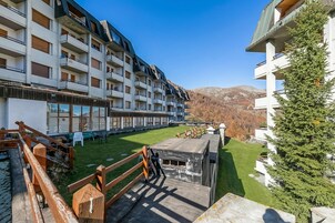 A multi-story hotel with balconies, a grassy courtyard, and a mountain backdrop.