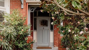 A brick house with a grey door, a small porch, and a doormat. - Family Home in central Sandy Bay (Sandy Bay)