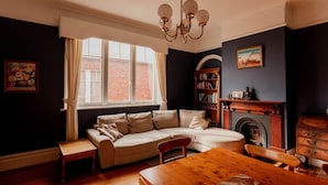 A cozy living room with a sofa, a wooden table, and a fireplace. - Family Home in central Sandy Bay (Sandy Bay)