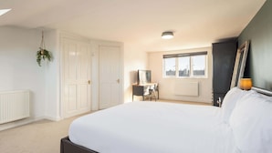 A bedroom with a large bed, a desk, a chair, a radiator, and a window with a view of buildings. - Host & Stay | Garnet Street (Saltburn-by-the-Sea)