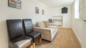 A waiting area with two black leather chairs, a beige sofa, and a small table with a chair. There are framed pictures on the wall and a window on the right. - Host & Stay | Garnet Street (Saltburn-by-the-Sea)