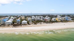 A coastal residential area with beachfront properties, including multi-story buildings with balconies, situated on sandy terrain with a view of the ocean. - Gulf Views w/ Pool, Firepit and Games (Port St. Joe)