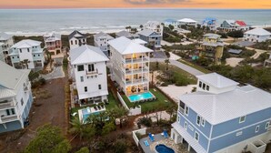 A coastal residential area with multiple two-story houses, each featuring a balcony and a small pool. - Gulf Views w/ Pool, Firepit and Games (Port St. Joe)