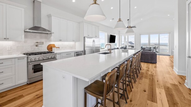 A modern kitchen with a large island, stainless steel appliances, and a view to the outside. - Gulf Views w/ Pool, Firepit and Games (Port St. Joe)