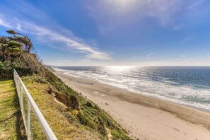 A coastal landscape with a beach, ocean, and a clear sky.