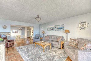 A spacious living room with a sofa set, a coffee table, and a chandelier.