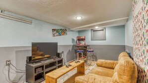 Una sala de estar con televisor, una mesa de centro de madera, un sofá de cuero y una consola de videojuegos.