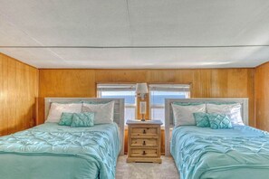 Ein Schlafzimmer mit zwei Betten, Holzwänden, einem Nachttisch und einem Fenster.
