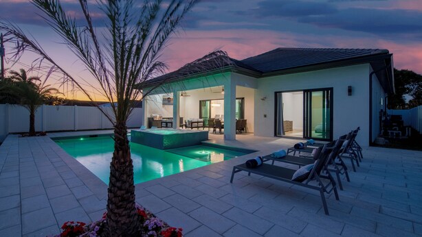 Une maison moderne dotée d’une piscine, d’un espace salon extérieur et d’un patio couvert.
