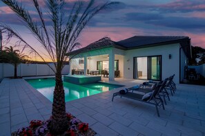 A modern house with a swimming pool, outdoor seating, and a covered patio area.
