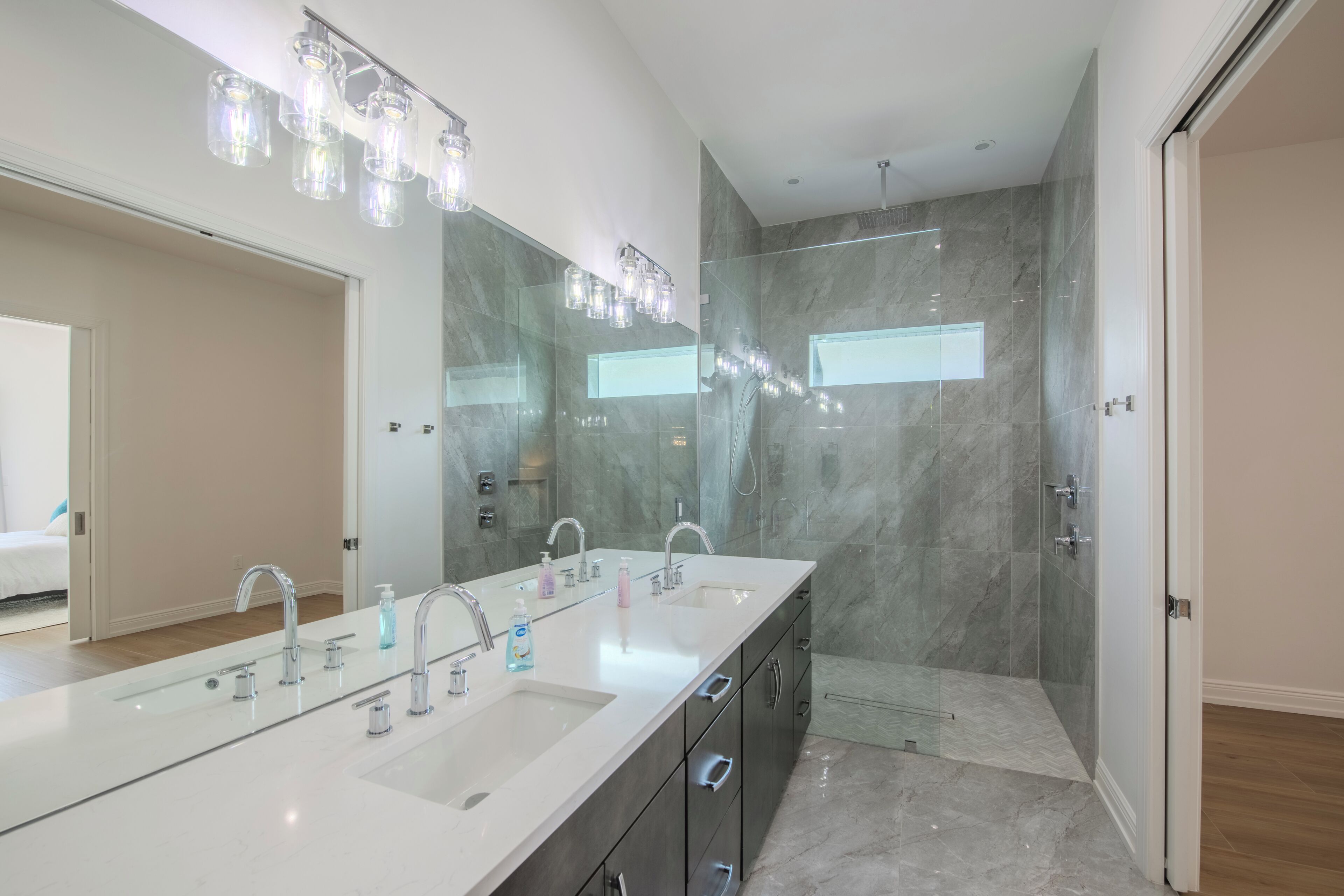 A modern bathroom with a large vanity, dual sinks, and a glass shower enclosure.