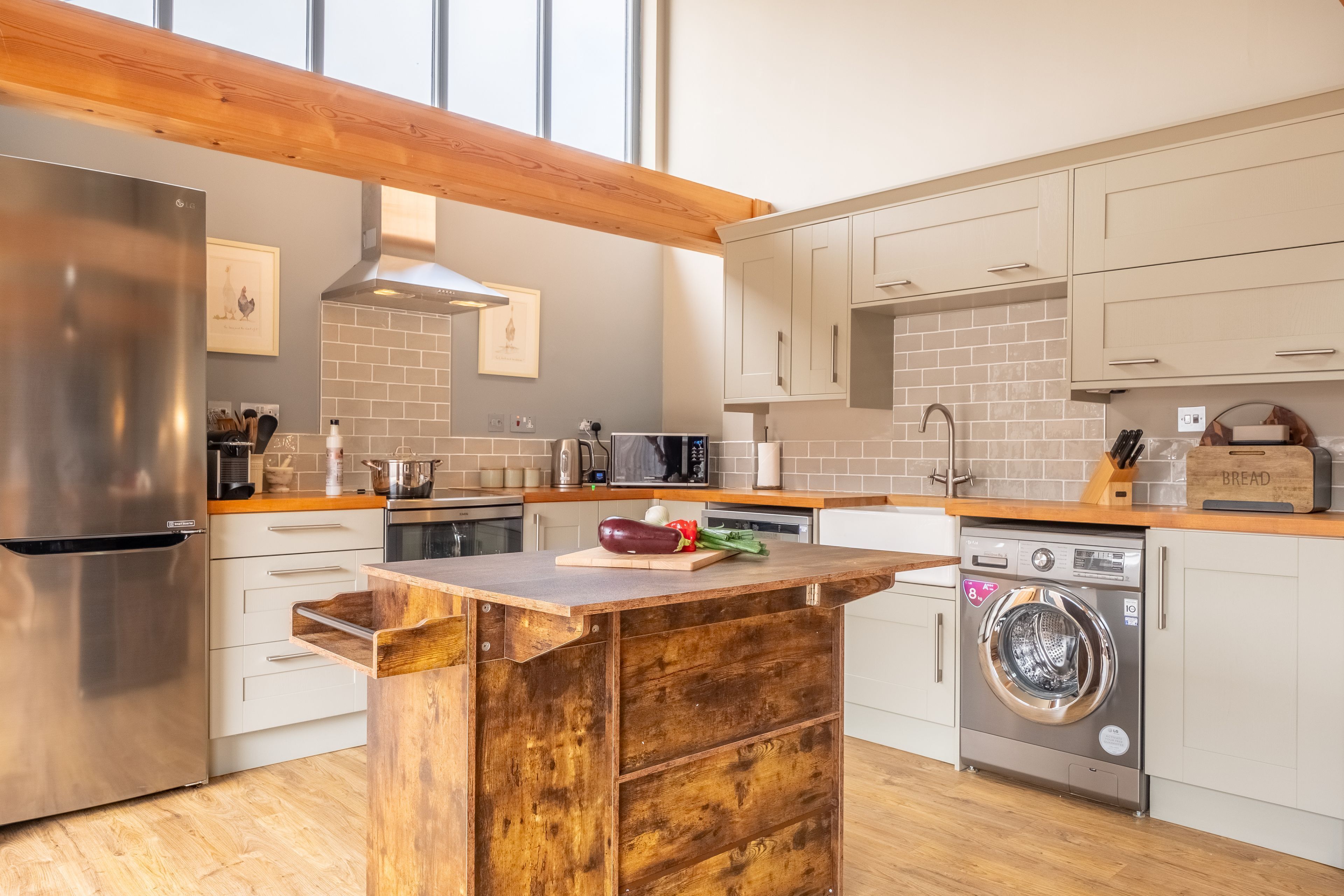A modern kitchen with a wooden island, stainless steel appliances, and a built-in washing machine.