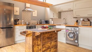A modern kitchen with a wooden island, stainless steel appliances, and a built-in washing machine.
