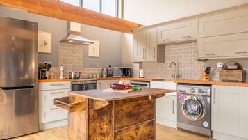 A modern kitchen with a wooden island, stainless steel appliances, and a built-in washing machine.
