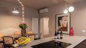Una cuina moderna amb una illa central, zona de menjador amb cadires i un quadre a la paret.