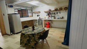 A compact kitchen with a dining table, chairs, a refrigerator, and a stove. - Amazonas Explorers Leticia (Leticia)