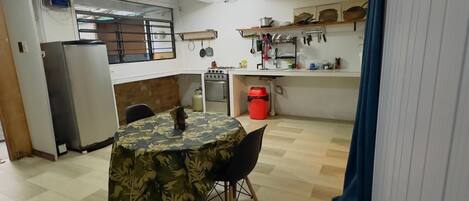 Uma cozinha compacta com mesa, cadeiras, geladeira e fogão.