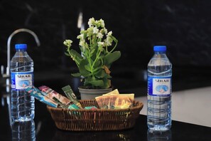 A table with two water bottles, a basket of snacks, and a potted plant. - Kristal Absheron 110 (Baku)