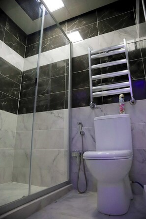 Un bagno con cabina doccia in vetro, un WC bianco e un portasciugamani.