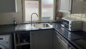 Una cocina con ventana, un fregadero, un tostador y armarios.