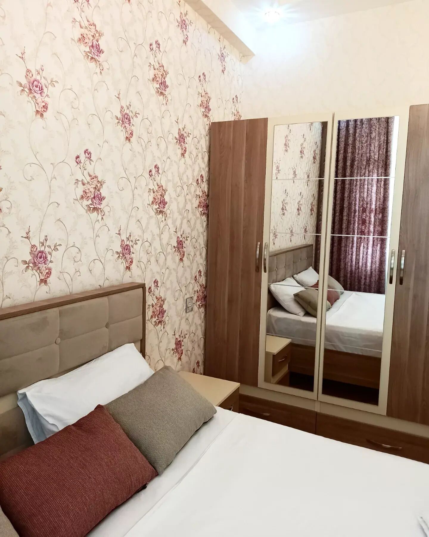 A bedroom with a bed, a wardrobe, and a mirror.