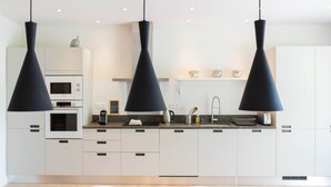 A modern kitchen with white cabinets, a built-in oven, and a black countertop. - Apartment les canisses (UZES)