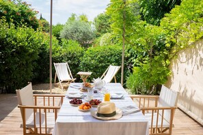 A table set outdoors with a view of lush greenery, two chairs, a tablecloth, and a hat. - Apartment les canisses (UZES)